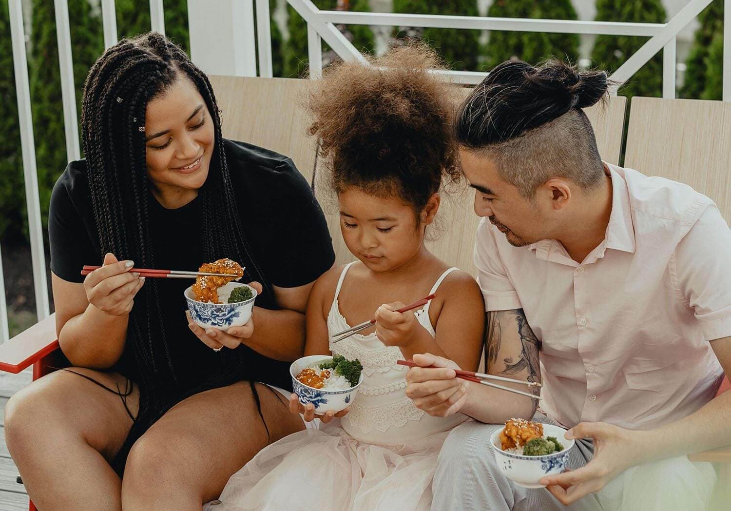 Image of family sitting on couch and eating food.